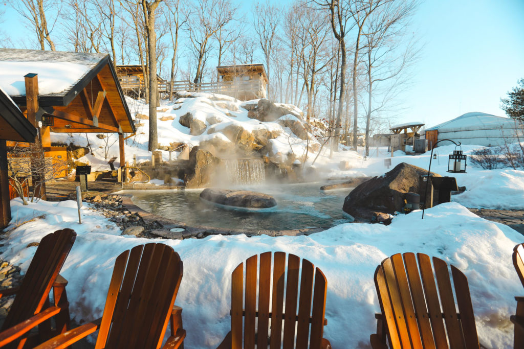 Un bassin d'eau chaude sous la neige dans le Nordik Spa-Nature au Québec en hiver